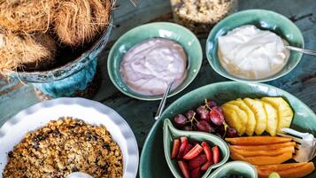 Taula amb diversos aliments, incloent un bol de granola, fruita fresca i dos bols de iogurt.