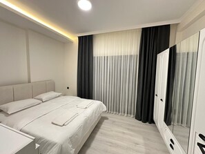 Ein modernes Schlafzimmer mit Bett, Nachttisch, Spiegel und einem Fenster mit Vorhängen.