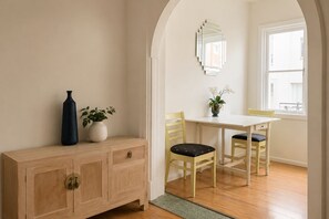 A room with a wooden cabinet, a table, two chairs, a vase with a plant, and a mirror on the wall. - Potts Point Cosy 1BR | Walk to CBD, Train, Cafes & Harbour! (Potts Point)