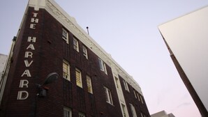 Ein hohes Backsteingebäude mit der Aufschrift 'THE HARVARD' an der Fassade.