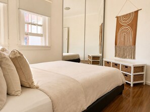 A bedroom with a bed, bedside tables, a mirror, and a window. - Potts Point Cosy 1BR | Walk to CBD, Train, Cafes & Harbour! (Potts Point)