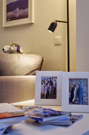 A room with a sofa, a lamp, framed pictures, and some papers on a table. - Entire Cascais New Mordern Apartment-3 Bedrooms (Cascais)