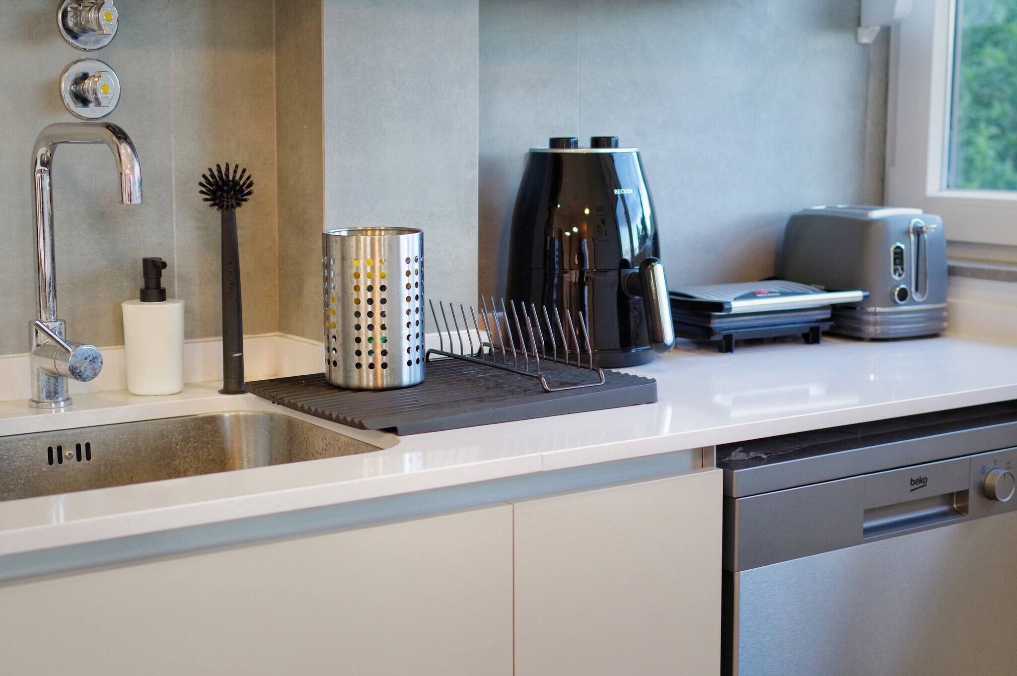 Une cuisine moderne équipée d’un évier en acier inoxydable, d’une machine à café et d’un grille-pain.