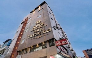 En flervåningsbyggnad med en skylt som visar texten ”TRP Hotel The Royal Palace”.