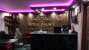 Un área de recepción con mostrador de mármol, una estatua y un letrero que dice 'TRP The Royal Palace Hotel'.