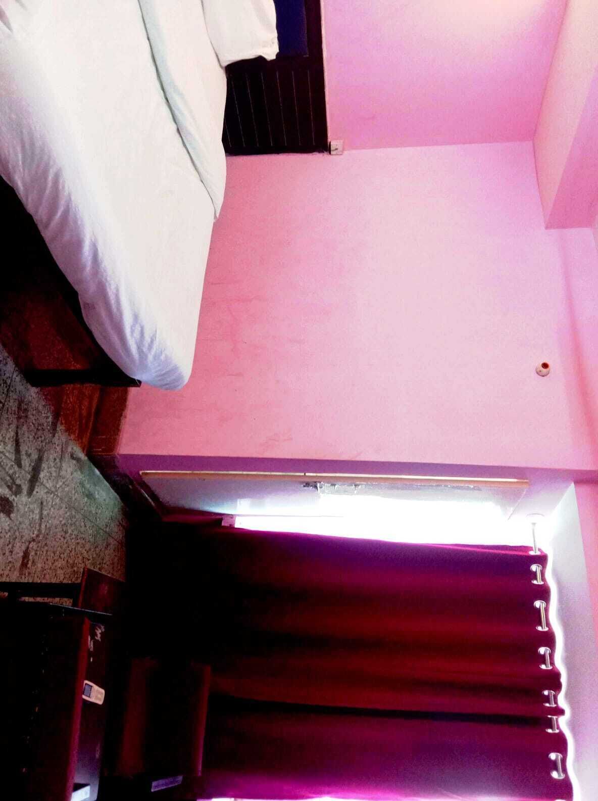 A room with a bed, a window with blinds, and a door.