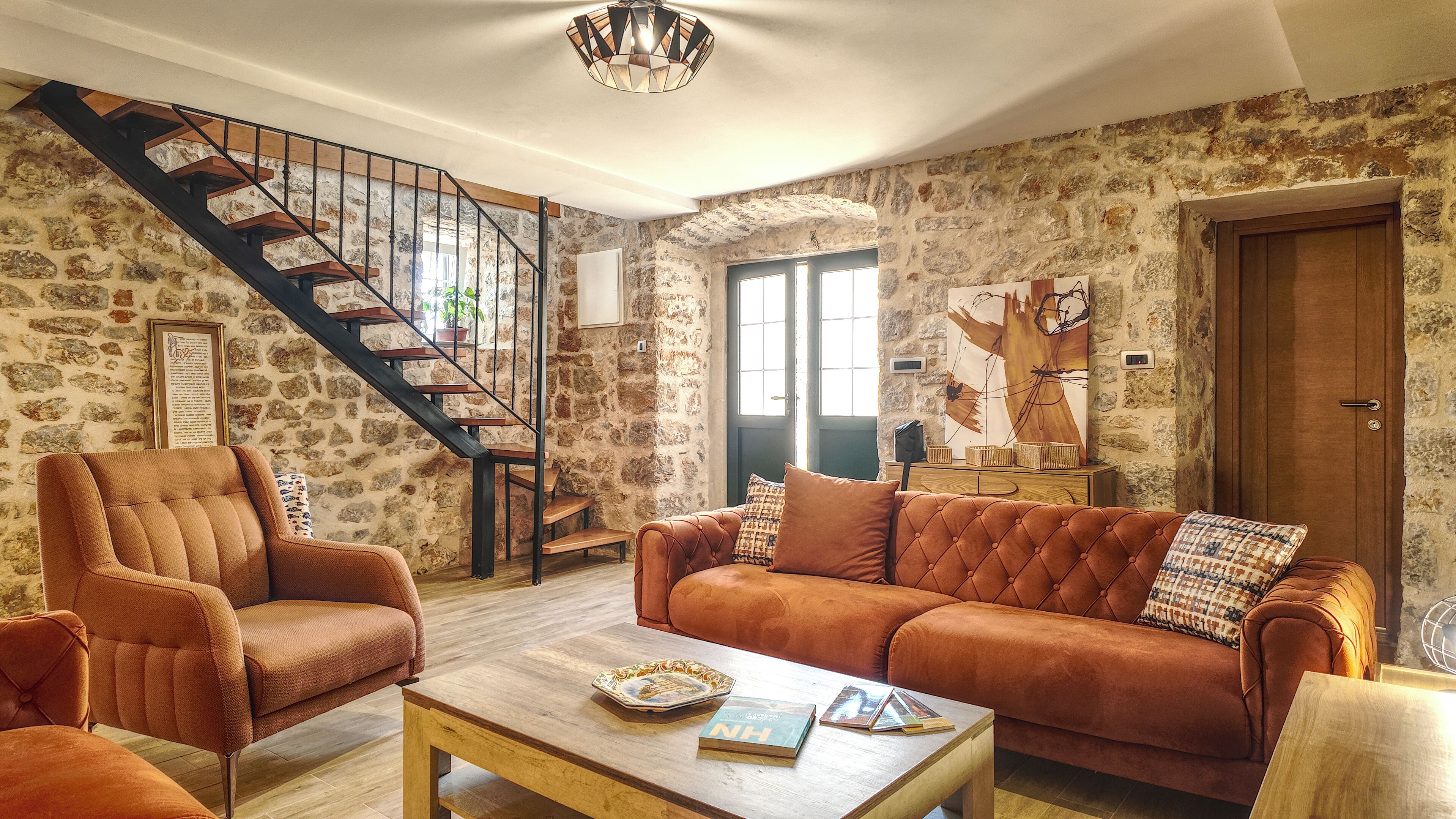 A living room with a staircase, a sofa, a coffee table, and a bookshelf.
