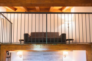 A wooden balcony with a metal railing, a sofa, and two wall-mounted lamps. - New Farmhouse TENUTA MARELLA immersed in the Green at the gates of Rome (Lazio)