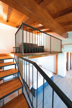 A wooden staircase with a metal railing leading to a loft bedroom with a bed and a sofa. - New Farmhouse TENUTA MARELLA immersed in the Green at the gates of Rome (Lazio)