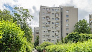 Un edificio residenziale a più piani con balconi, immerso nel verde e con un viale lastricato.