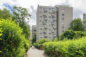 Ein mehrstöckiges Wohngebäude mit Balkonen, umgeben von üppigem Grün und einem gepflasterten Weg.