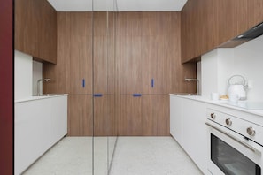 Eine moderne Küche mit Holzausziehtüren, einer weißen Arbeitsplatte und einem eingebauten Backofen.