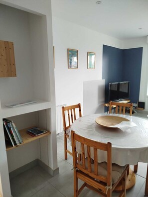 Un comedor con una mesa redonda, sillas de madera, una estantería y cuadros en la pared.
