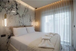 Ein Hotelzimmer mit Bett, Marmorwand, Vorhängen und einem Fenster.