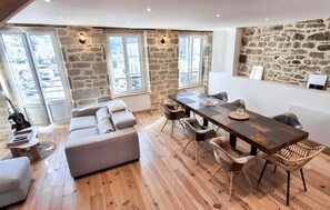 Un coin repas avec une table en bois, des chaises et un mur en pierre.