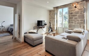 Un salon moderne avec un mur en pierre, un téléviseur et une guitare.