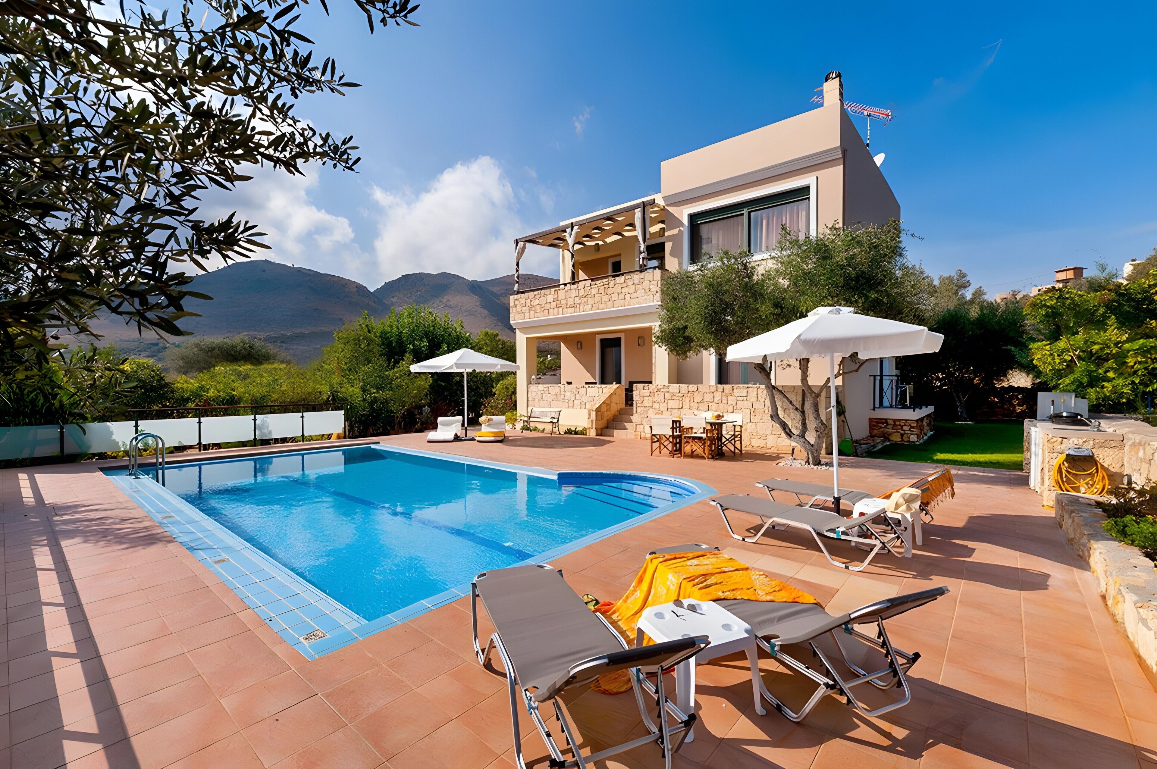 A poolside area with lounge chairs, a swimming pool, and a building with a balcony.. Villa Renata with Private Pool, Mountain View, Wi-Fi, and Air Conditioning