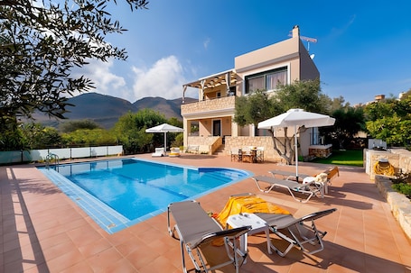 A poolside area with lounge chairs, a swimming pool, and a building with a balcony.. Villa Renata with Private Pool, Mountain View, Wi-Fi, and Air Conditioning