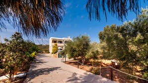 A pathway leading to a building with a modern architectural style, surrounded by greenery and trees. - Villa Renata with Private Pool, Mountain View, Wi-Fi and Air Conditioning (Aptera)