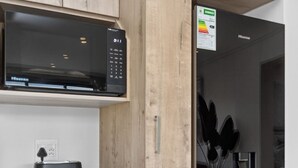 Ett kompakt kök med tvättmaskin, mikrovågsugn och kylskåp.