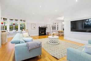 A spacious living room with a sofa, round coffee table, and a fireplace.