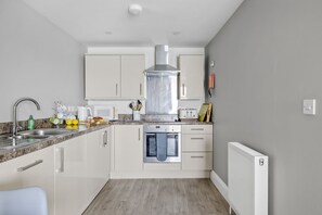 A modern kitchen with white cabinets, stainless steel appliances, and a granite countertop. - Marina View Suite, Astor House - Sea view, 250 meters from beach (Torquay)