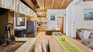 A cozy kitchen with wooden cabinets, a dining table with chairs, and a living area with a sofa and a painting on the wall. - Holiday Home Villa Le Punte (Rovinj)