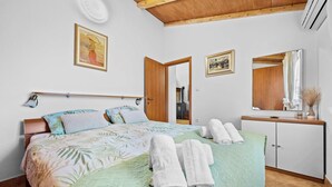A bedroom with a bed, a bedside table, a mirror, and a door. - Holiday Home Villa Le Punte (Rovinj)