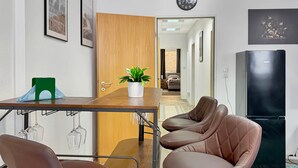 A modern kitchen with a wooden table, two brown chairs, a potted plant, and a black refrigerator.