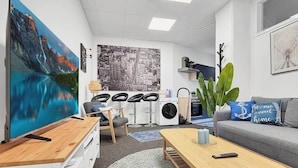 Una sala de estar moderna con un televisor de pantalla plana grande, un sofá, una mesa de centro y un comedor.