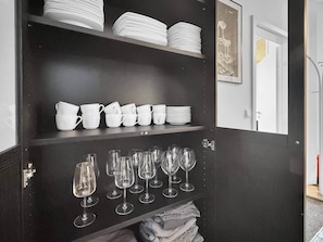 A dark wooden cabinet with white dishes and glasses. - Loft 26 Stuttgart | PS5, Darts, 12 Gäste (Stuttgart)