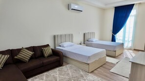A hotel room with two beds, a sofa, and an air conditioning unit. - Latin District Apartments Lagoon Side (Latin District, New Alamein)