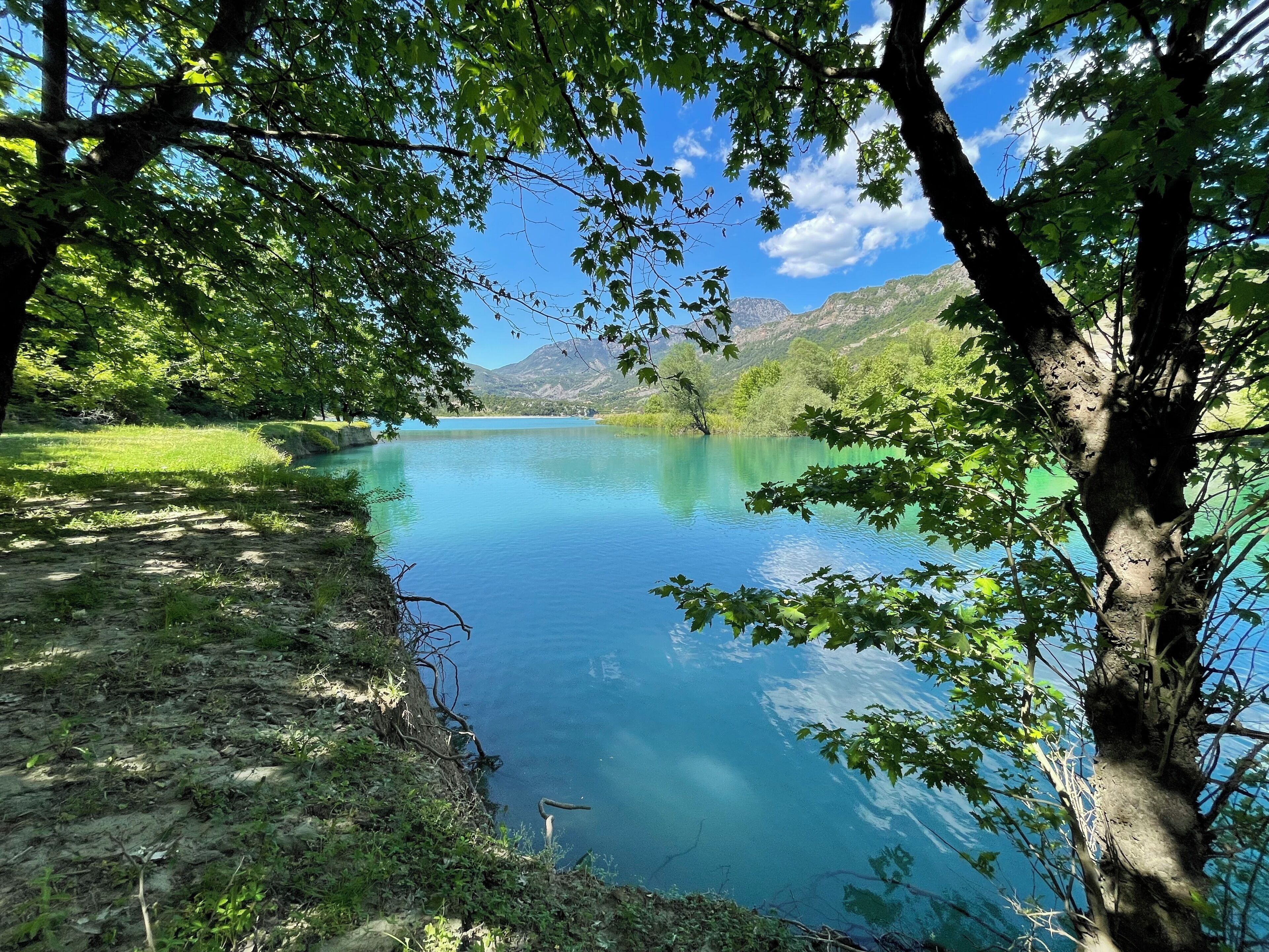 A serene lake surrounded by lush greenery and mountains.