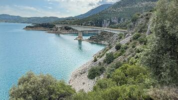 Paesaggio costiero con un ponte, acqua blu cristallina e colline verdi.