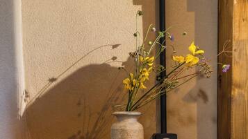 A rustic wooden stump with a vase of flowers and a clock.