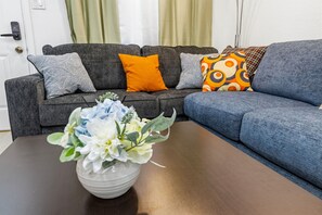 Ein Wohnzimmer mit grauem Sofa, blauem Sofa und Couchtisch mit Blumenarrangement.