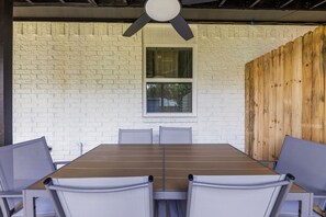 A dining area with a long table and six chairs, a window, and a ceiling fan. - 3BR Near AT&T Stadium | Free Parking (Arlington)