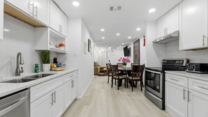 A modern kitchen with white cabinets, a dining area with a table and chairs, a built-in oven, and a microwave. - Spacious 3BR Retreat • Sleeps 6 • Free Parking (Arlington)