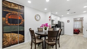 A modern dining area with a round table, chairs, a clock, and a large abstract painting. - Spacious 3BR Retreat • Sleeps 6 • Free Parking (Arlington)
