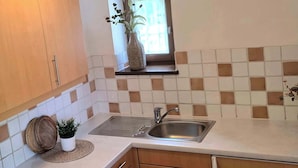 A compact kitchen with wooden cabinets, a stainless steel sink, and a window with a view. - Alpine Retreat Apt: Scenic Bavarian Nature, (Fischbachau)