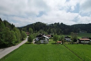 A rural village with houses surrounded by green fields and a forested hill.