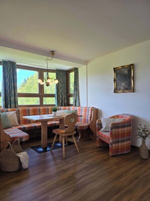 Ein gemütliches Zimmer mit Holztisch, karierter Möbel und einem Gemälde an der Wand.