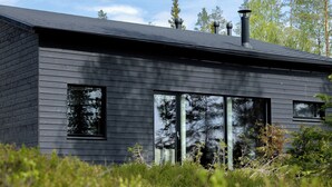 A modern building with a dark exterior, large windows, and a chimney. - Villa Noel B (Lappi)
