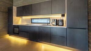 A modern kitchen with built-in appliances, a window, and a wooden floor. - Villa Noel B (Lappi)