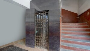 A staircase with a metal gate leading to a room with dark tiled walls and a light-colored floor.