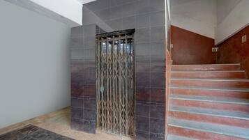 A staircase with a metal gate leading to a room with dark tiled walls and a light-colored floor.