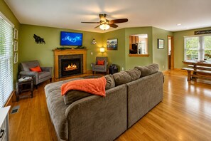 A living room with a fireplace, sofa, television, and a ceiling fan. - Large Pet Friendly Home! Games, Firepit & More! (Sevierville)