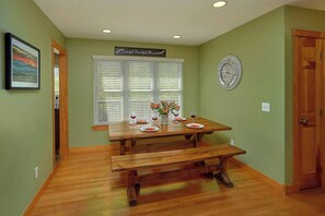 A dining area with a wooden table, benches, and a clock on the wall. - Large Pet Friendly Home! Games, Firepit & More! (Sevierville)