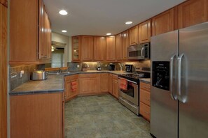A kitchen with wooden cabinets, stainless steel appliances, and a tiled floor. - Large Pet Friendly Home! Games, Firepit & More! (Sevierville)