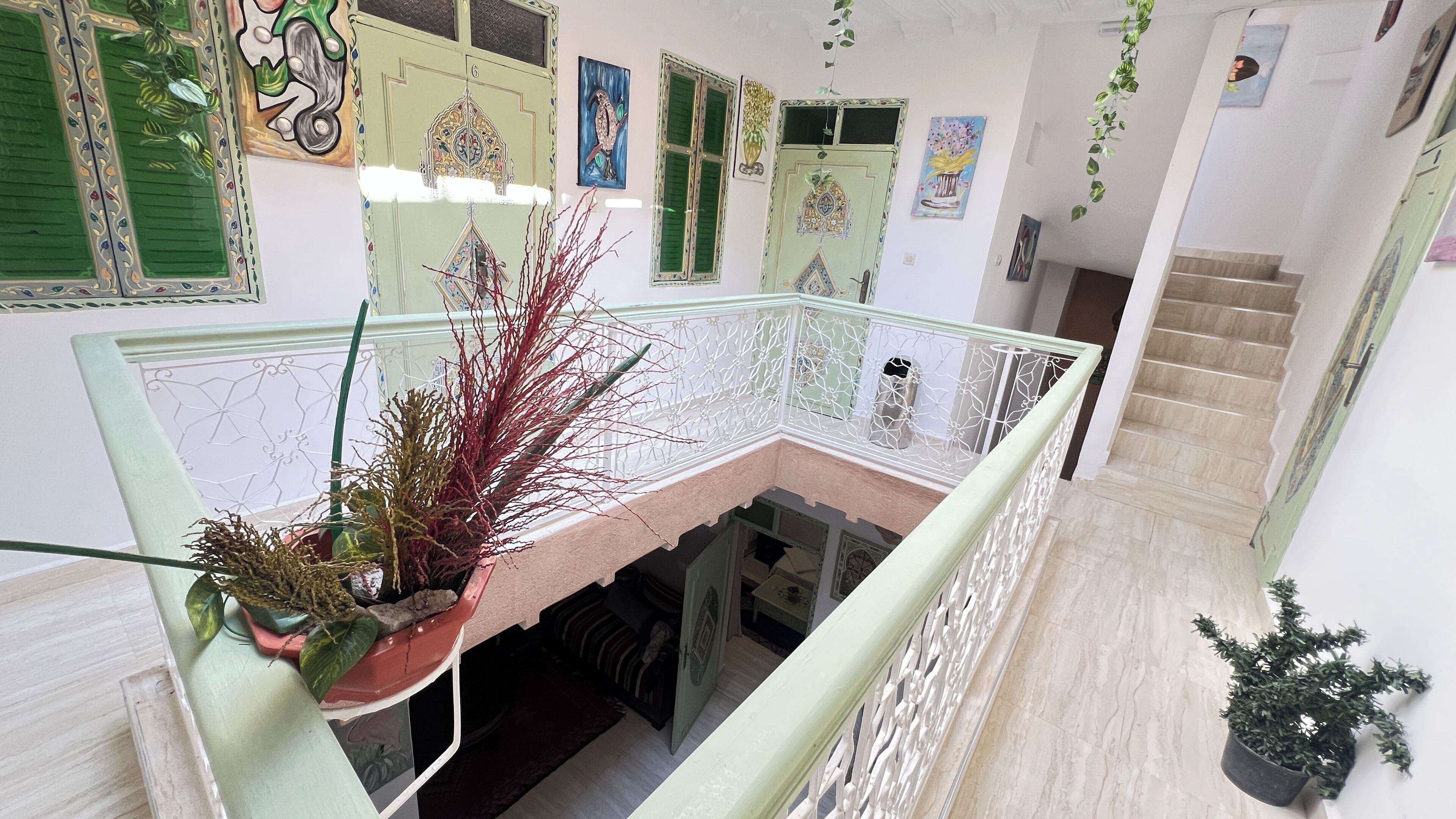 Ein mehrgeschossiges Interieur mit Balkon, Wanddekoration und Topfpflanzen.
